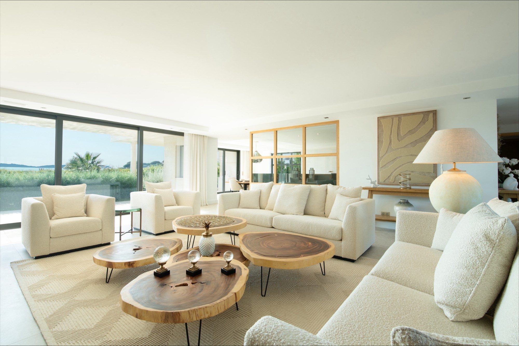 Grand salon blanc et tables en bois massif face à la mer