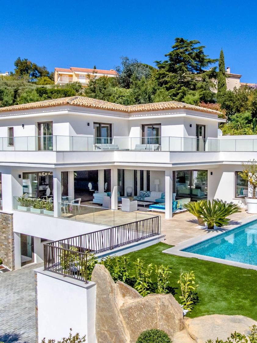 White villa and its pool among palm trees
